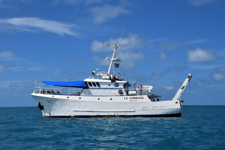 Navio de pesquisa navegando em águas calmas sob céu aberto.