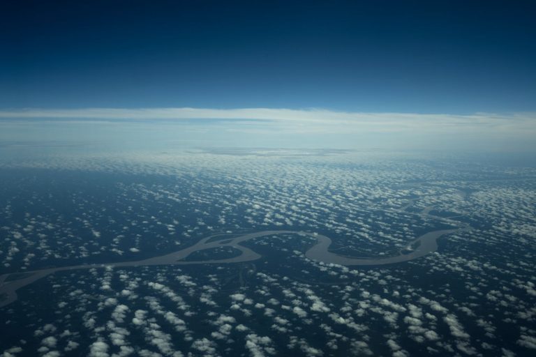 Vista aérea de um rio sinuoso atravessando uma extensa área de floresta no Brasil.